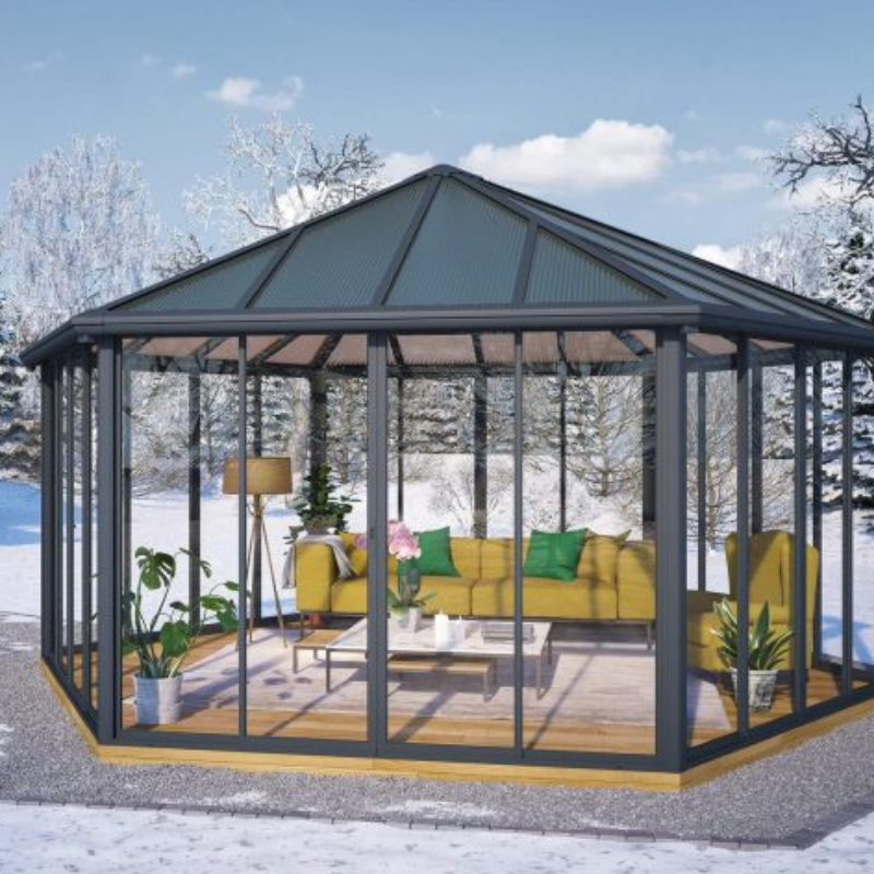 The Palram-Canopia Garda conservatory designed as a lounging area in a snowy winter garden setting.