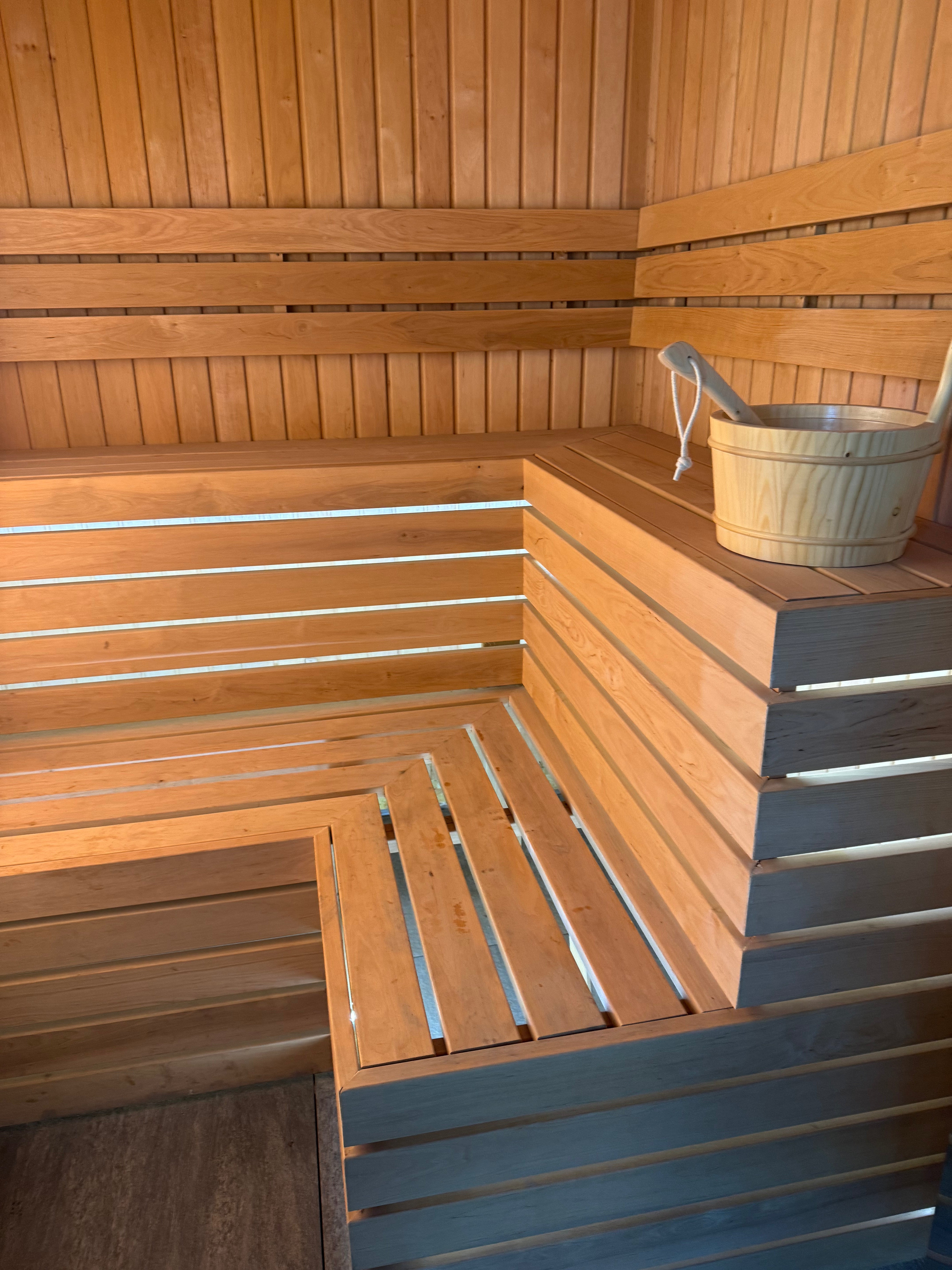 Wooden sauna interior with a bucket on a raised platform.