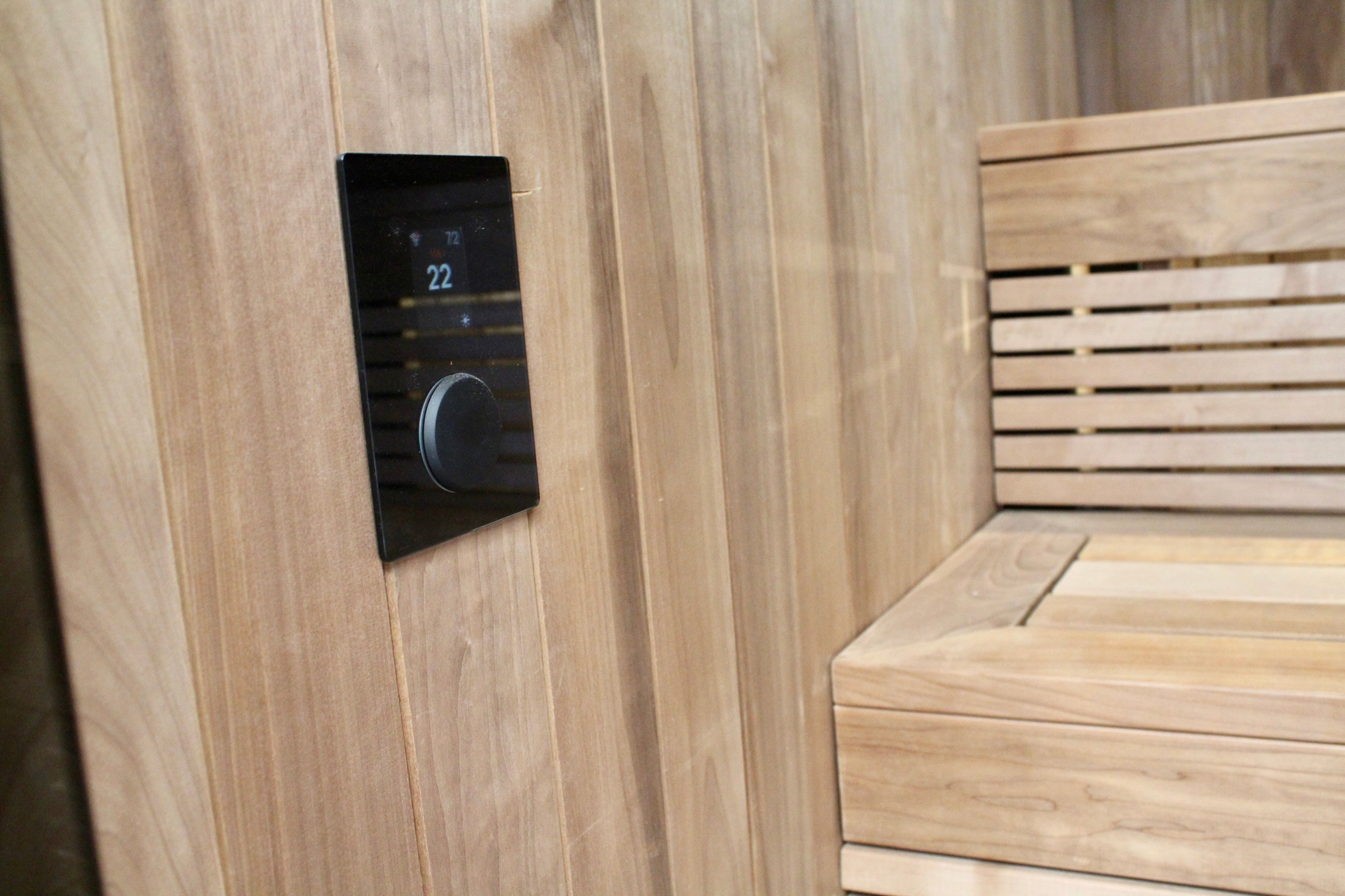 Wooden sauna interior with a digital temperature control panel.