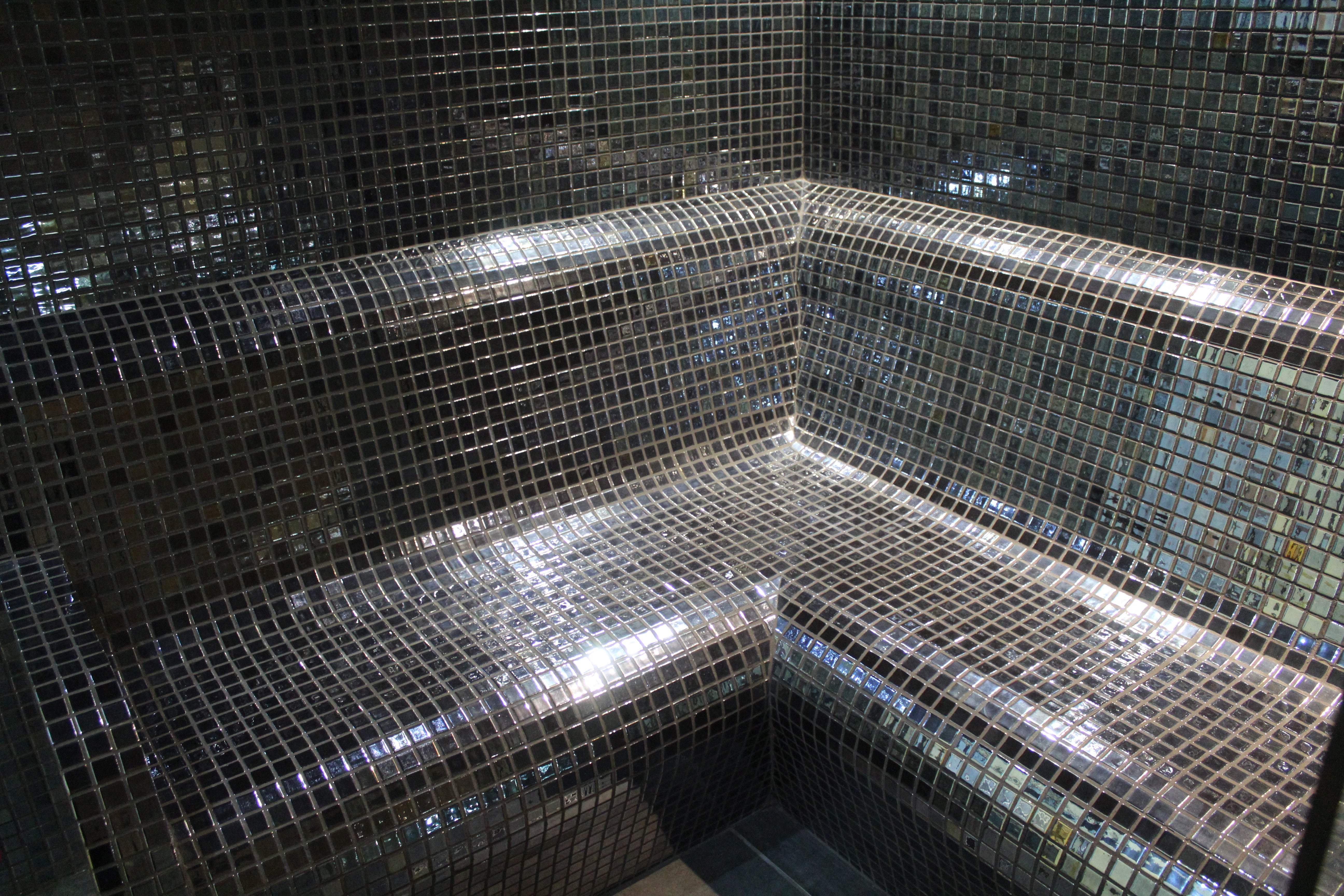 Mosaic tiled bench in a dimly lit steam room