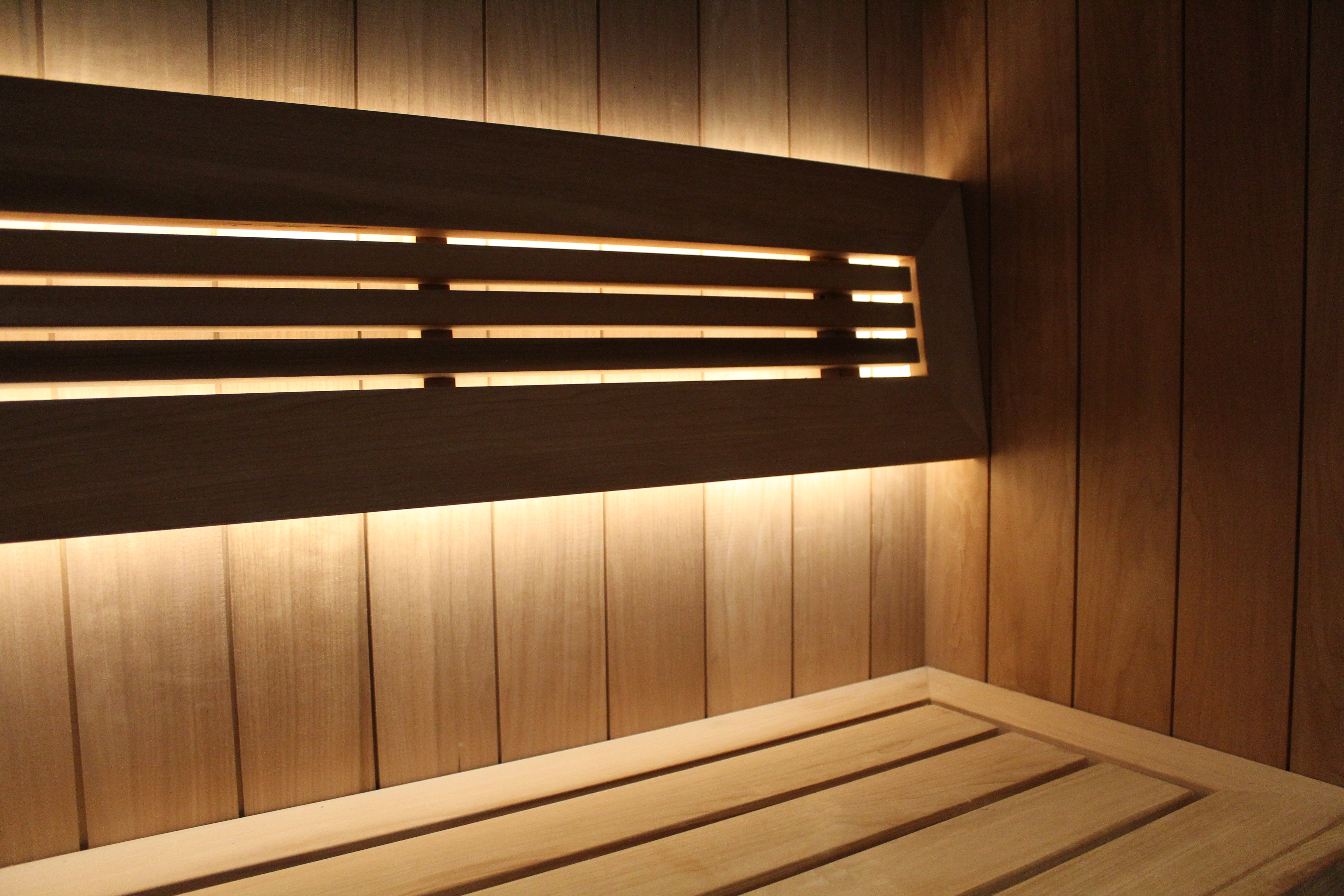 Wooden sauna bench with embedded lighting against a wooden wall.