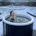 Polar Recovery Cyclone wooden ice bath in black, woman bathing in snowy garden