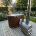 Polar Recovery Ember wood fired hot tub, couple relaxing with stove on decking