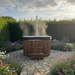 Polar Recovery Ember wood fired hot tub, steaming on stone garden patio