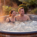 Polar Recovery Royal round wood fired hot tub, couple relaxing in bubbling water