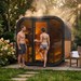Polar Recovery Sauna Cube 6-8 person outdoor sauna with glass front, couple and steam at sunset
