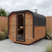Polar Recovery Sauna Cube 6-8 person outdoor sauna with wood front and wood burner flue in a garden